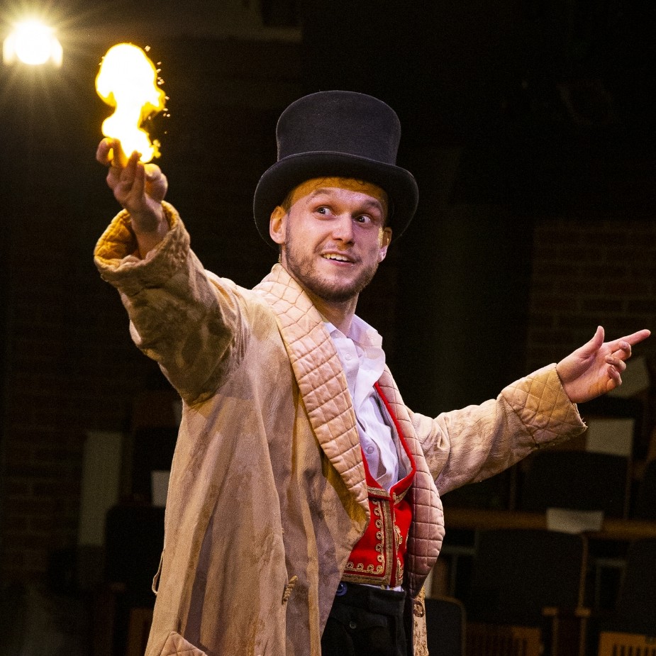 A wizard in a gold robe and a top hat conjures a fireball.