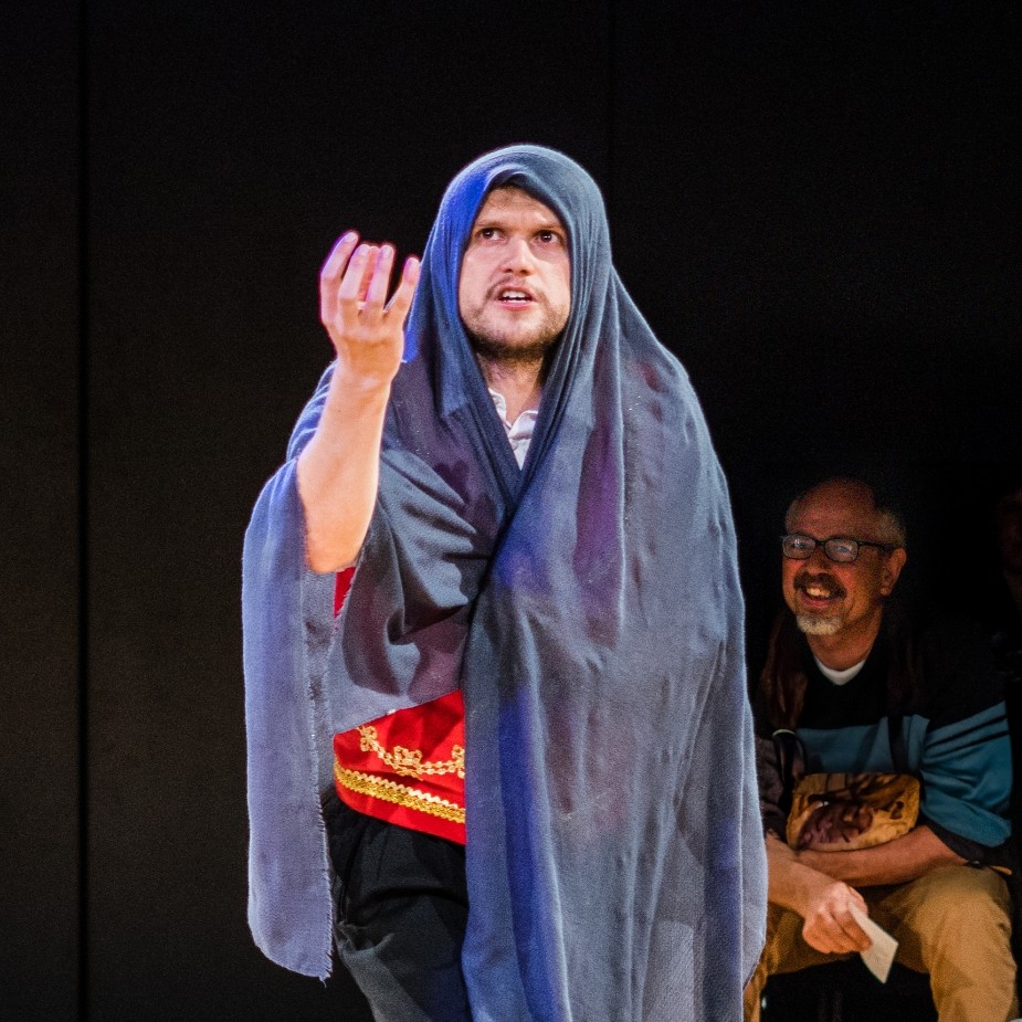 A witch in a blue shawl summons a spell from the air.